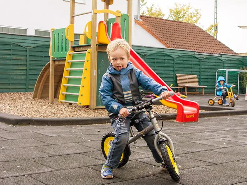 Boy on a balance bike making a funny face near the playground slide