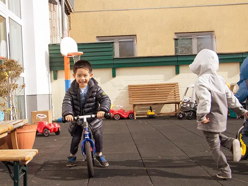 Smiling boy riding a balance bike in the school playground courtyard