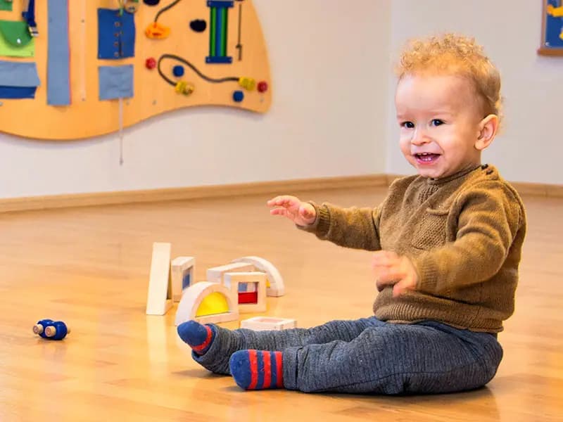 Toddler in the ages 1-3 classroom choosing a practical life tray from the shelf