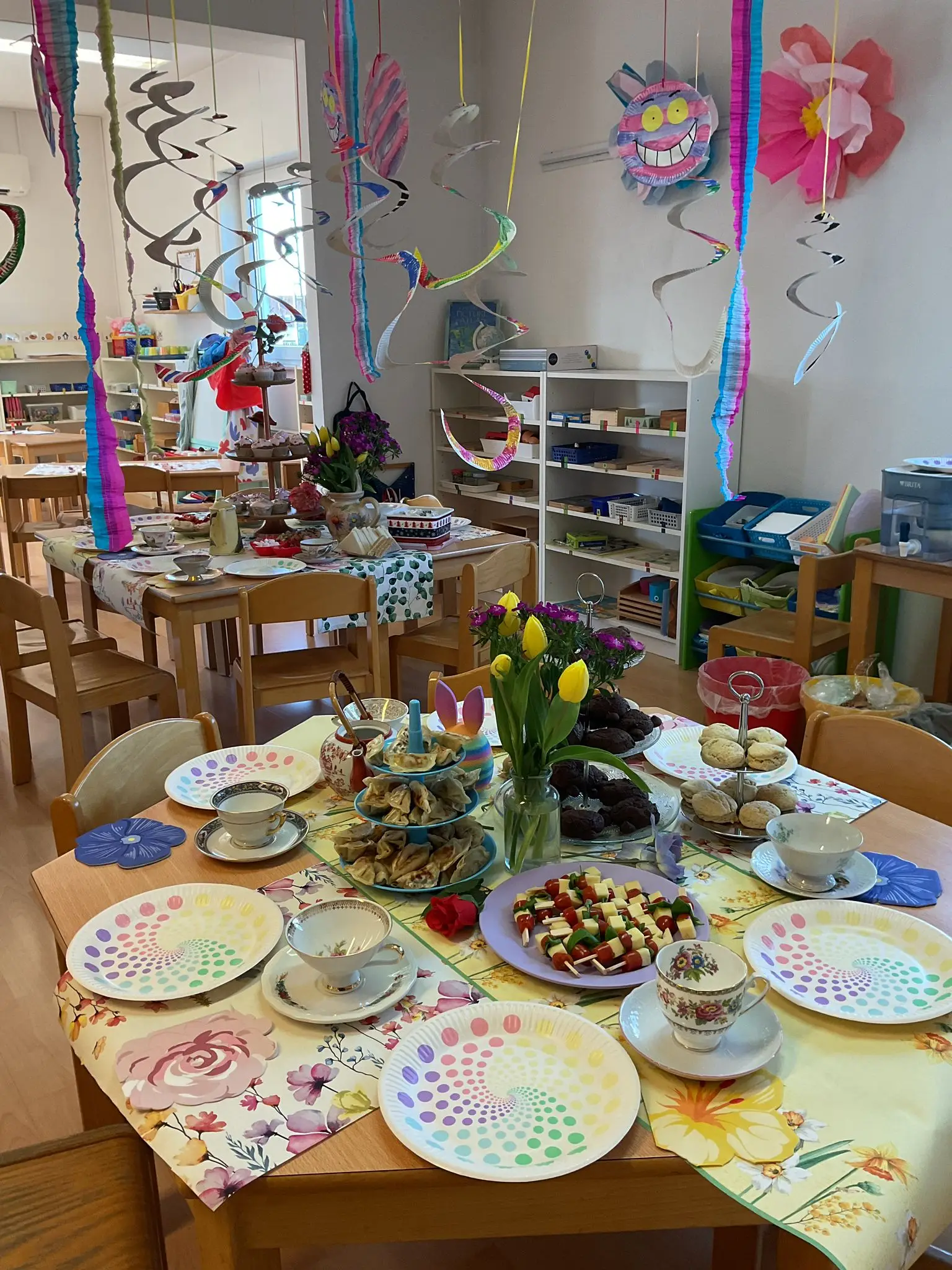 Classroom decorated for an Easter tea party with treats and colorful table settings