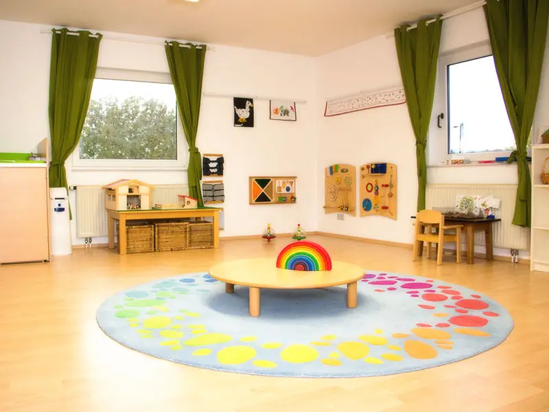 Empty TIMS toddler classroom with a colorful round rug and sensory materials